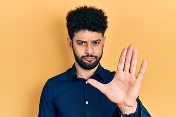 Young arab man with beard wearing casual shirt doing stop sing with palm of the hand. warning...