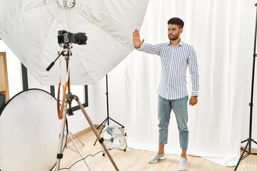 Arab young man posing as model at photography studio doing stop sing with palm of the hand. warning...