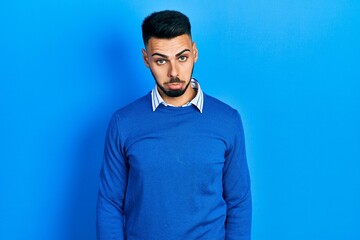 Young hispanic man with beard wearing casual blue sweater depressed and worry for distress, crying angry and afraid. sad expression.