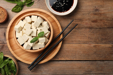 Obraz na płótnie Canvas Delicious tofu with basil served on wooden table, flat lay. Space for text