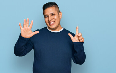 Young latin man wearing casual clothes showing and pointing up with fingers number seven while smiling confident and happy.