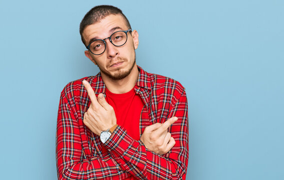 Hispanic young man wearing casual clothes pointing to both sides with fingers, different direction disagree