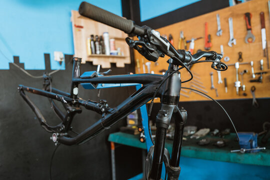 close up of a black bicycle frame without wheels hanging in the workshop