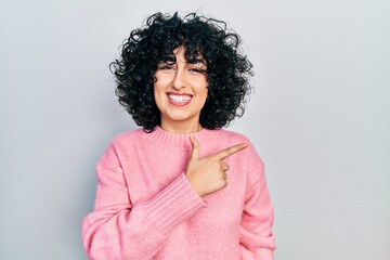 Fototapeta premium Young middle east woman wearing casual clothes cheerful with a smile on face pointing with hand and finger up to the side with happy and natural expression
