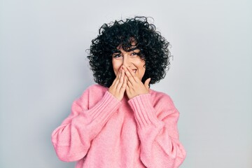 Young middle east woman wearing casual clothes laughing and embarrassed giggle covering mouth with...