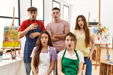 Group of five hispanic artists at art studio afraid and shocked with surprise expression, fear and excited face.