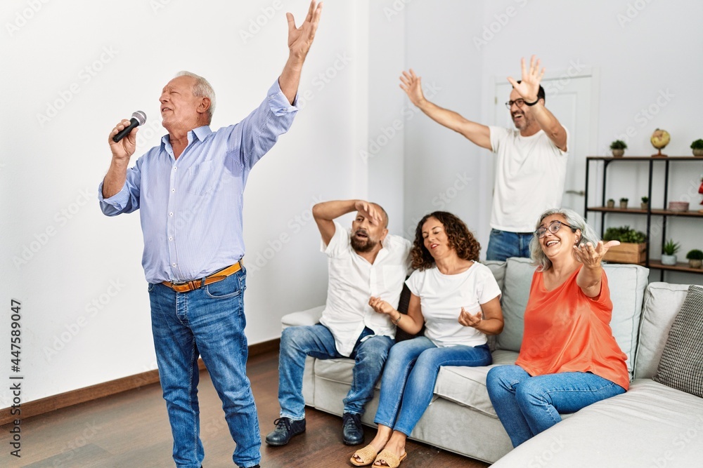 Poster group of middle age friends having party singing song using microphone at home.