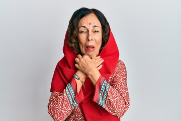 Middle age hispanic woman wearing tradition sherwani saree clothes shouting and suffocate because...