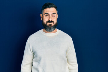 Obraz premium Young hispanic man wearing casual clothes puffing cheeks with funny face. mouth inflated with air, crazy expression.