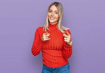 Beautiful blonde woman wearing casual clothes pointing fingers to camera with happy and funny face. good energy and vibes.