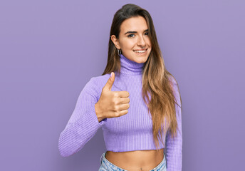 Young hispanic woman wearing casual clothes doing happy thumbs up gesture with hand. approving expression looking at the camera showing success.