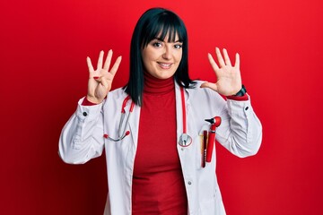 Young hispanic woman wearing doctor uniform and stethoscope showing and pointing up with fingers number nine while smiling confident and happy.