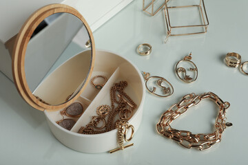 Jewelry box with mirror and stylish golden bijouterie on table