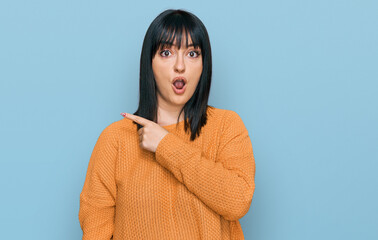 Fototapeta premium Young hispanic woman wearing casual clothes surprised pointing with finger to the side, open mouth amazed expression.