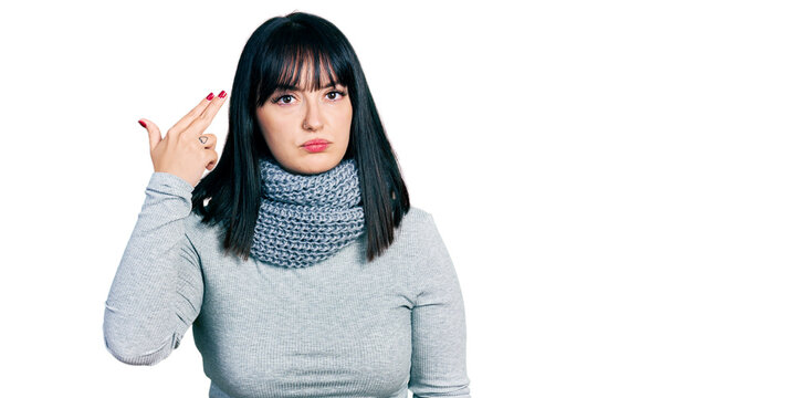 Young hispanic plus size woman wearing winter scarf shooting and killing oneself pointing hand and fingers to head like gun, suicide gesture.