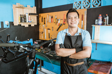 Portrait of a handsome repairman in an apron as work clothes in a bicycle repair shop