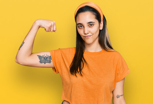 Young hispanic woman wearing casual clothes strong person showing arm muscle, confident and proud of power