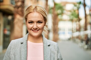 Young blonde businesswoman smiling happy standing at the city.