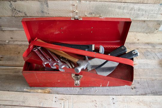Old red retro handyman toolbox on wooden background.