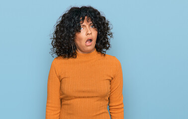 Young hispanic woman wearing casual clothes in shock face, looking skeptical and sarcastic,...