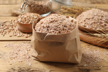 Paper bag with wheat bran on wooden table