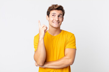 young handsome man smiling happily and looking sideways, wondering, thinking or having an idea