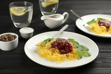 Tasty spaghetti squash with tomato sauce, cheese  and basil served on black wooden table