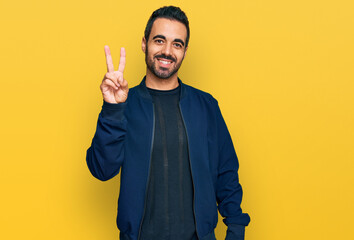 Young hispanic man wearing casual clothes showing and pointing up with fingers number two while smiling confident and happy.