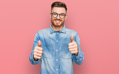 Young redhead man wearing casual denim shirt success sign doing positive gesture with hand, thumbs...