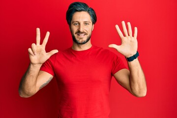 Naklejka premium Young hispanic man wearing casual red t shirt showing and pointing up with fingers number eight while smiling confident and happy.
