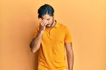 Young hispanic man wearing casual yellow t shirt tired rubbing nose and eyes feeling fatigue and headache. stress and frustration concept.