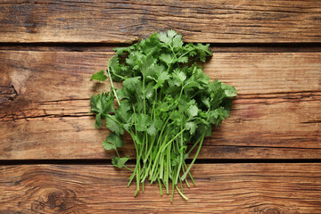 Bunch of fresh aromatic cilantro on wooden table, top view