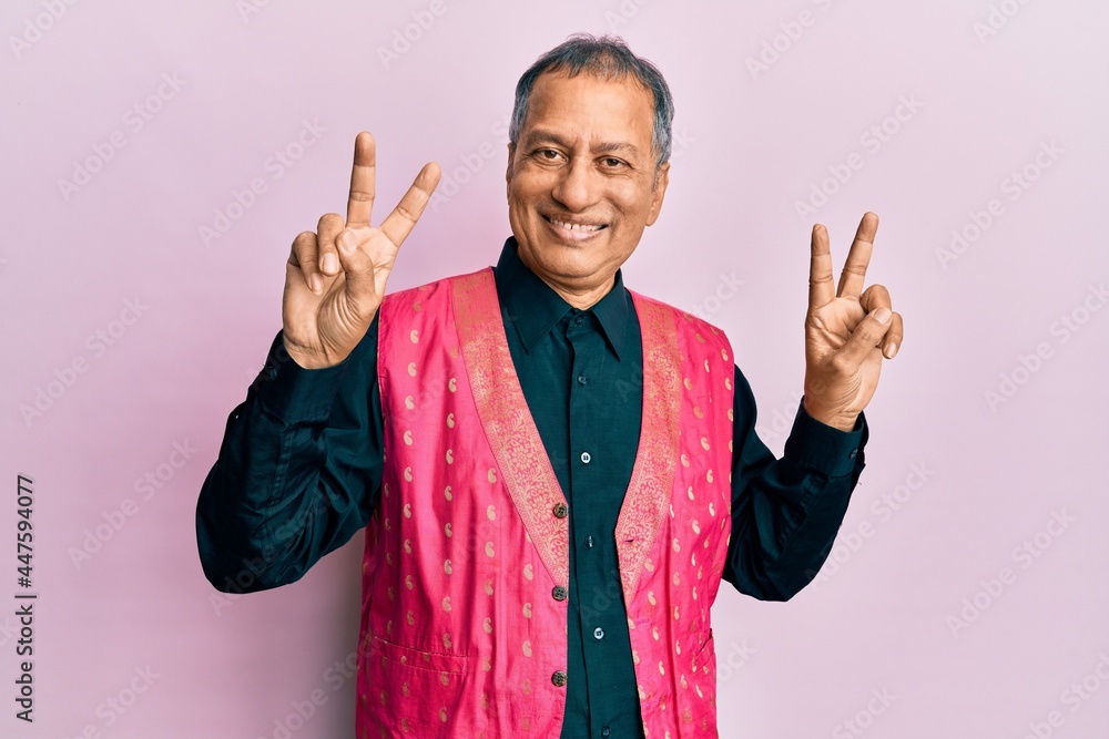 Canvas Prints middle age indian man wearing traditional indian clothes smiling looking to the camera showing finge