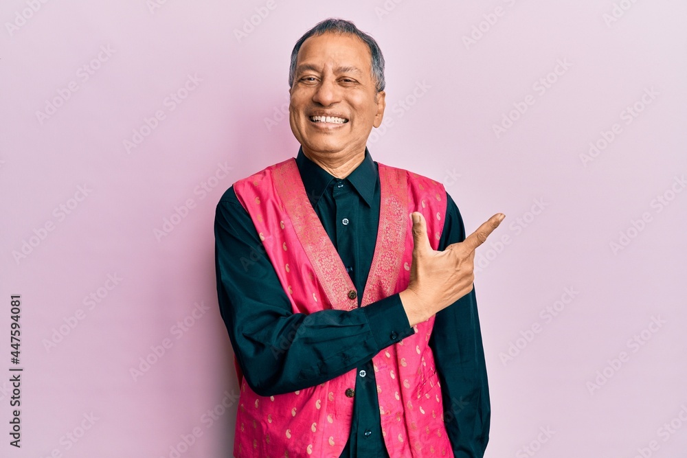 Poster Middle age indian man wearing traditional indian clothes cheerful with a smile of face pointing with hand and finger up to the side with happy and natural expression on face