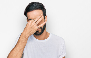 Young hispanic man wearing casual white t shirt tired rubbing nose and eyes feeling fatigue and headache. stress and frustration concept.