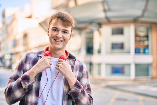 Young caucasian man smiling happy using headphones at the city.