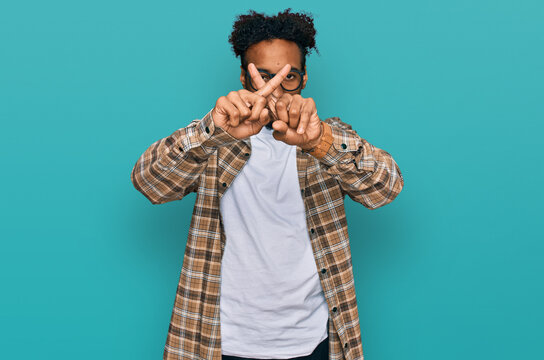 Young african american man with beard wearing casual clothes and glasses rejection expression crossing fingers doing negative sign