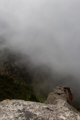 The top of three ancient monoliths viewed from another monolith peak with andean forest mountains at background in foggy day