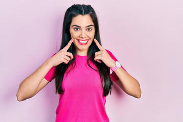 Young hispanic girl wearing casual pink t shirt smiling with open mouth, fingers pointing and forcing cheerful smile