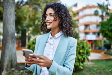 Young hispanic business woman wearing professional look smiling confident at the city using smartphone