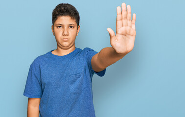 Teenager hispanic boy wearing casual clothes doing stop sing with palm of the hand. warning...