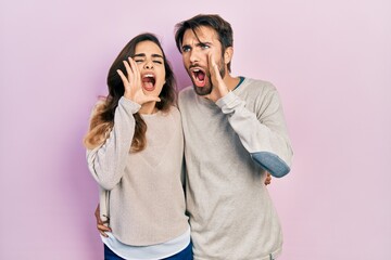 Young hispanic couple wearing casual clothes shouting and screaming loud to side with hand on mouth. communication concept.