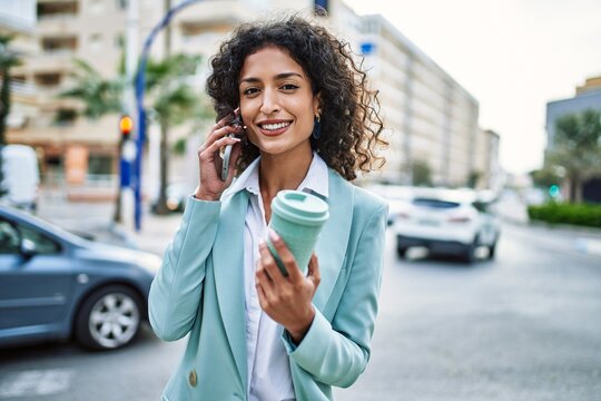 Young hispanic business woman wearing professional look smiling confident at the city speaking on the phone