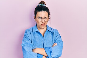 Young hispanic woman wearing casual clothes and glasses skeptic and nervous, disapproving expression on face with crossed arms. negative person.