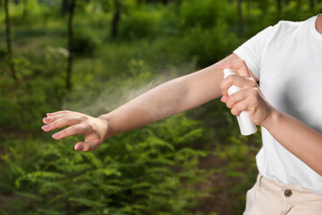 Woman applying insect repellent on arm in park, closeup. Tick bites prevention