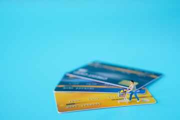 shopping ecommerce concept : Miniature figurine shoppers, carts, on mock up credit card and blue background. consumer order or buy things from retail store over the internet