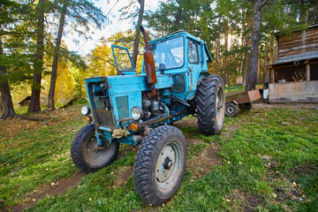 An old blue tractor stands in a farmyard