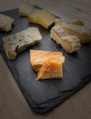 pieces of aged cheese served on a slate board resting on a wooden table