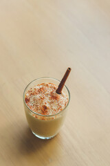 Top view shot of sweet tasty creamy spiced homemade eggnog alcoholic beverage celebrate Thanksgiving Christmas eve New year party in glass with gingerbread on wooden table background with copy space