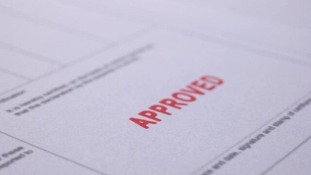 Business financial document with stamping message with rubber stamp. Closeup document marked with approved stamp